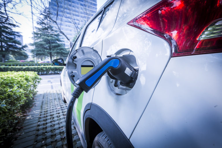 Elektrische wagen die oplaadt op parking van het kantoor.