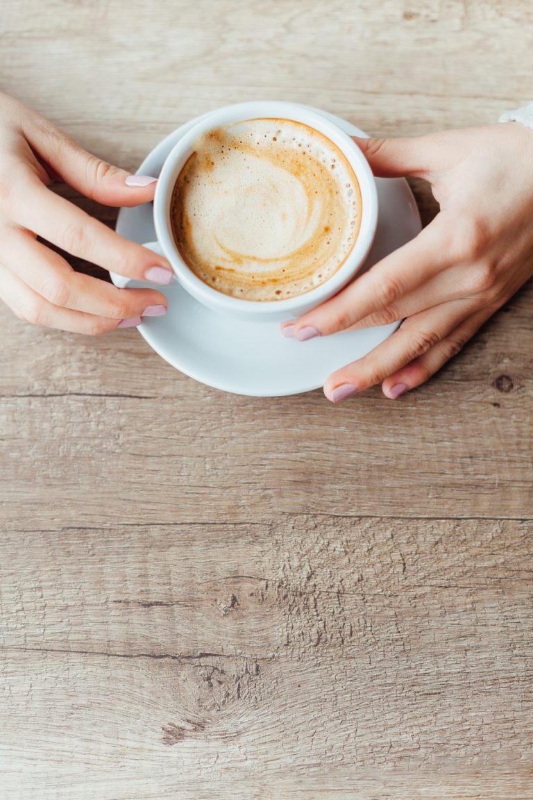 Twee handen die een tas koffie vasthouden.