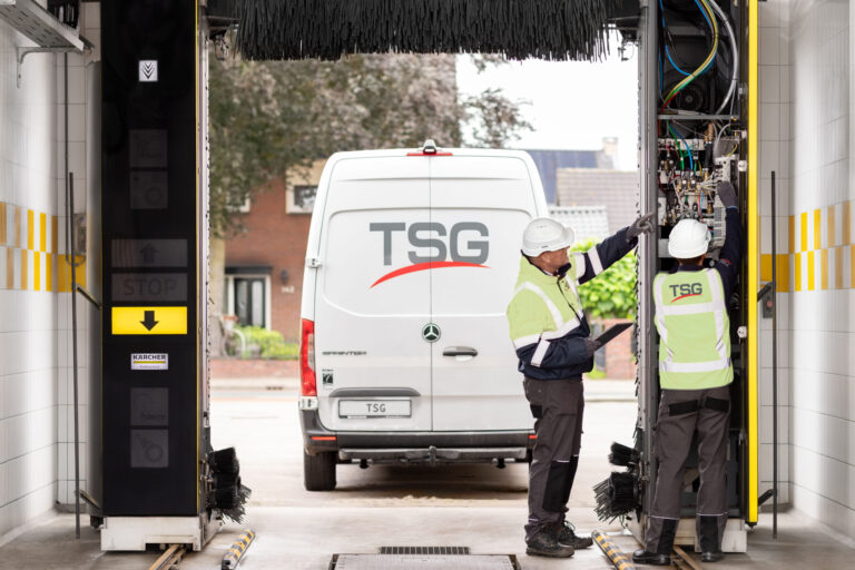 Twee techniekers van TSG die een roll-over installeren met op de achtergrond een TSG-van.