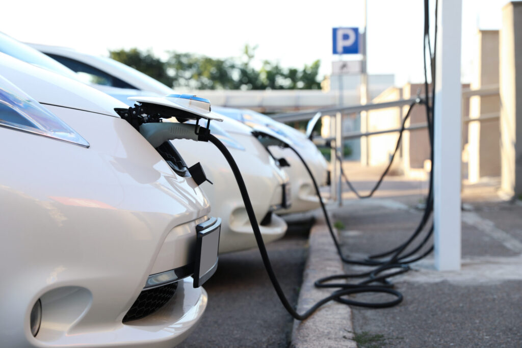 Véhicules électriques qui rechargent à une borne de recharge sur un parking.