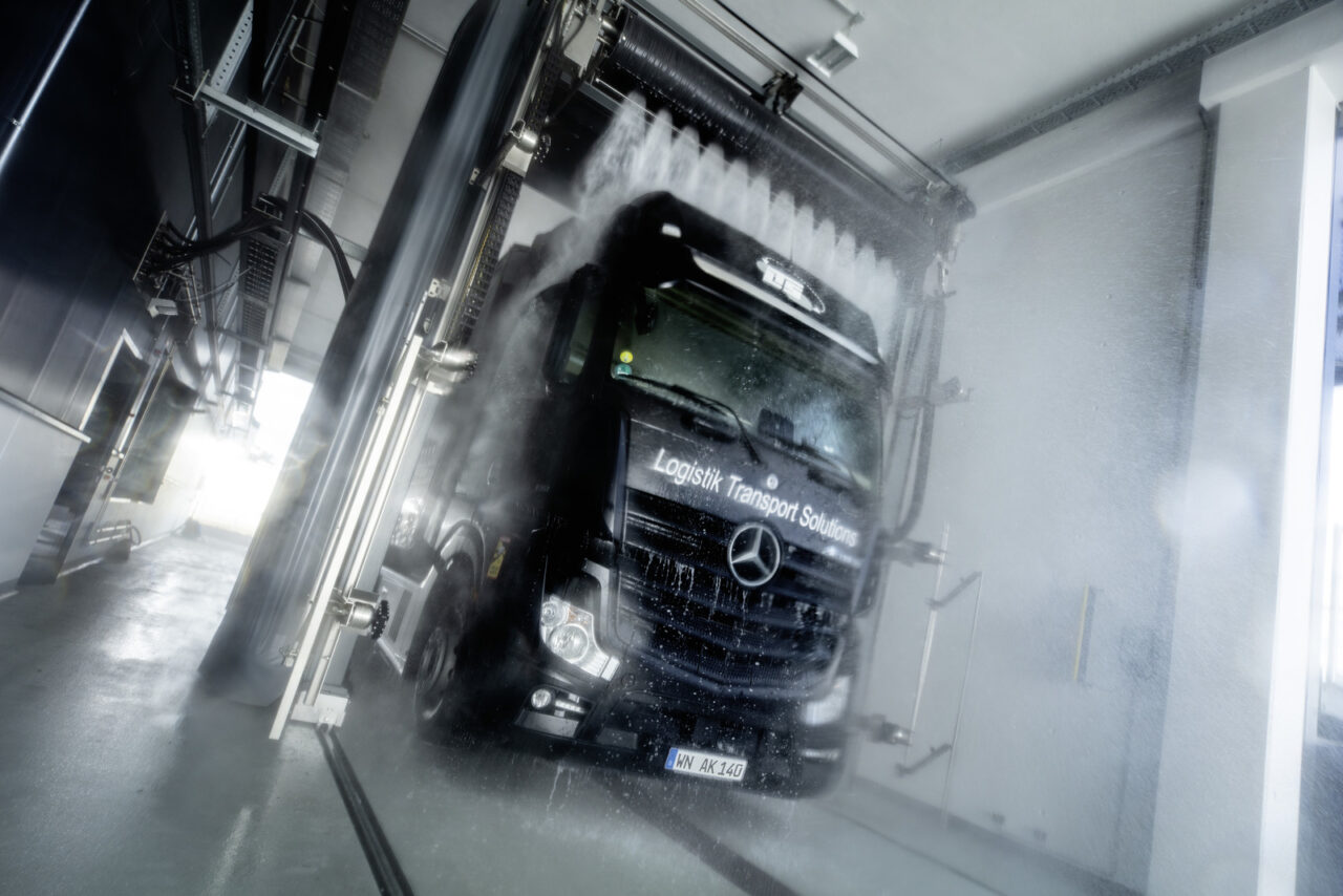Zwarte vrachtwagen in truckwash van Kärcher. Hoge drukreiniger is aan het werk op het dak van de vrachtwagen.