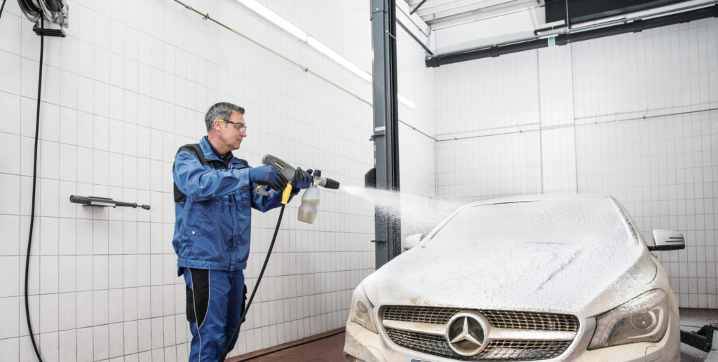 Man wast een witte wagen in self carwash.