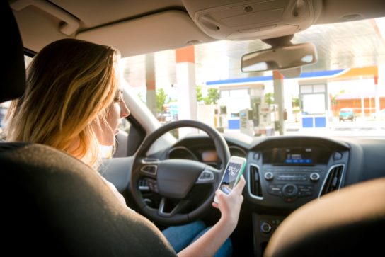 Vrouw betaalt tanksessie met behulp van MobyPay op haar gsm in de wagen.