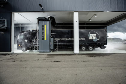Un portique de lavage camions avec un camion noir dedans.