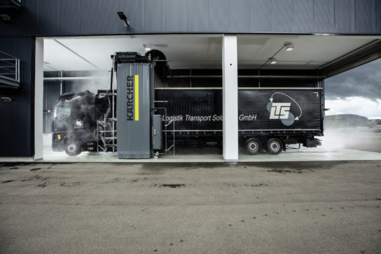 Un portique de lavage camions avec un camion noir dedans.