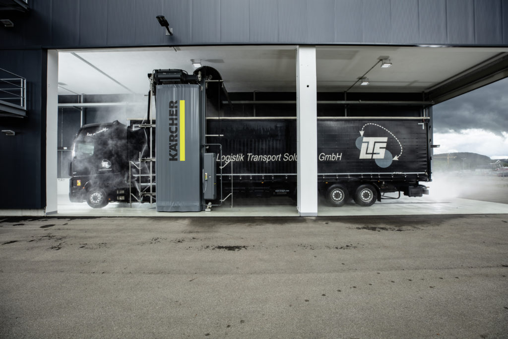 Truckwash van Kärcher in overdekte washal met een zwarte vrachtwagen in die wordt gewassen.