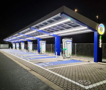 Een verlicht laadplein met blauwe details voor elektrische voertuigen op een droge avond