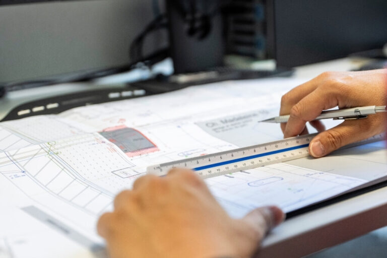 Planification d’une station-service : un spécialiste mesure les plans de construction à la règle